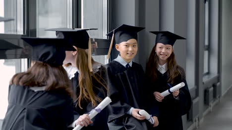 group of happy  preschool students in mortarboard and gown 2