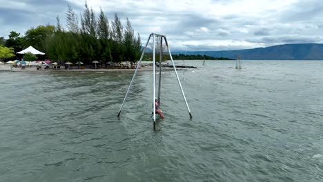 Unique-location-to-relax-and-play,-young-girl-on-swing-on-lake-shore