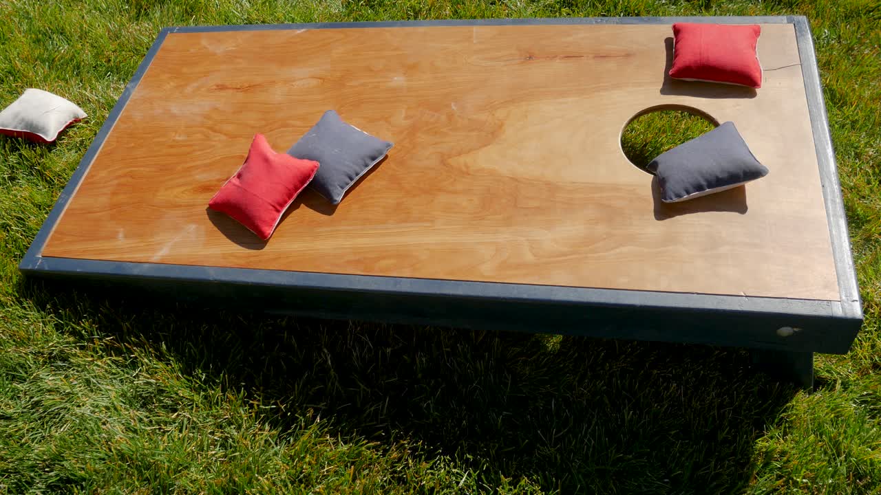 toma aislada de un tablero de cornhole cuando las bolsas de maíz caen sobre él durante un juego