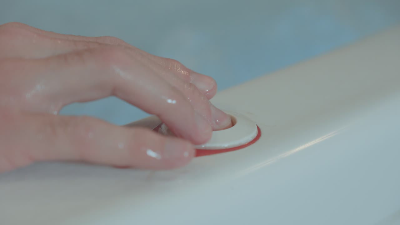 una mano presiona el botón de parada del jacuzzi