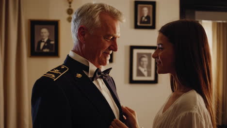 a woman assists a man in a military uniform indoors