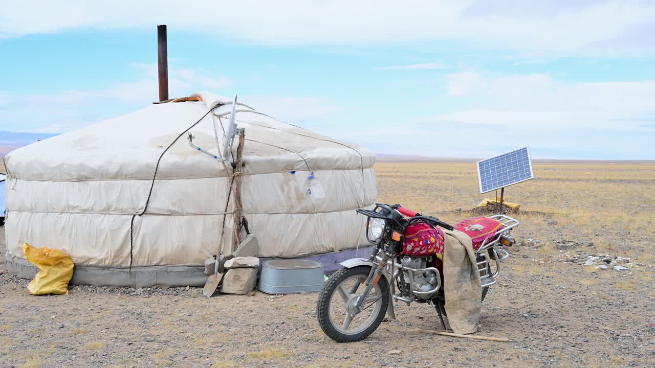 A blend of old and new on the Mongolian steppe: a modern motorcycle and a solar panel stand outside a traditional nomadic ger. A scene of adaptation and changing lifestyles