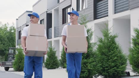 Two young workers of removal company deliver boxes to a customer's home