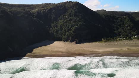 steep mountain ranges and hiking trails along black sand beach on new zealand's west coast