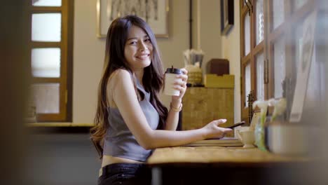 asian women playing phone and drinking hot coffee in coffee shop.