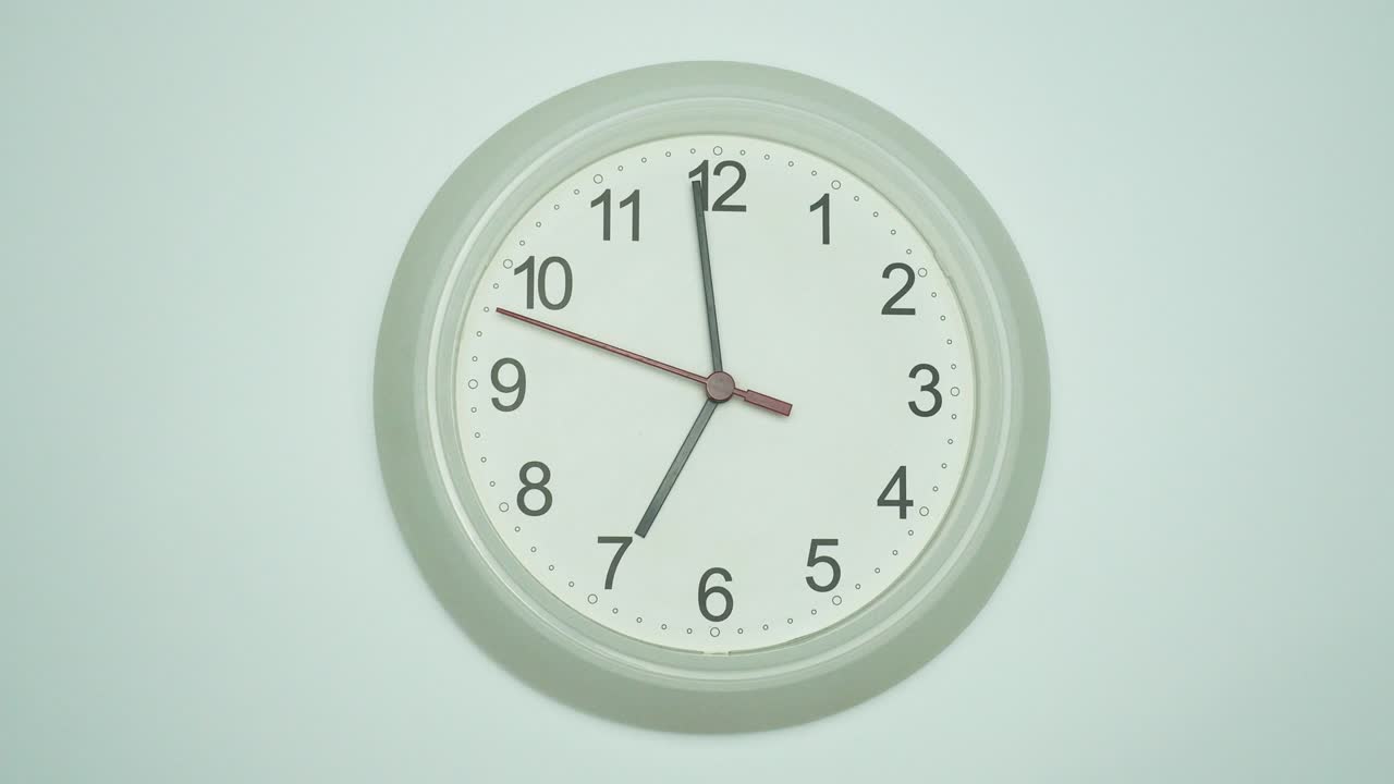 Orologio da parete bianco che segna un minuto alle sette.