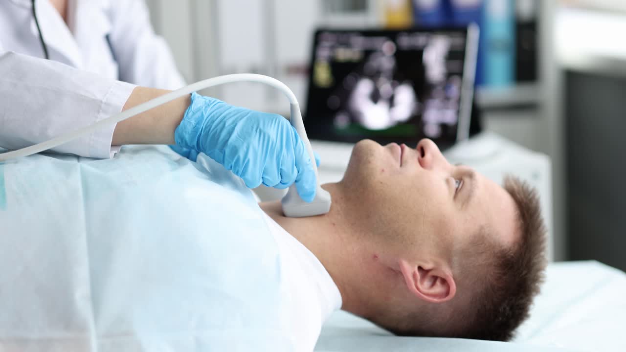 Uomo esamina la tiroide con sonda ecografica in uno studio medico