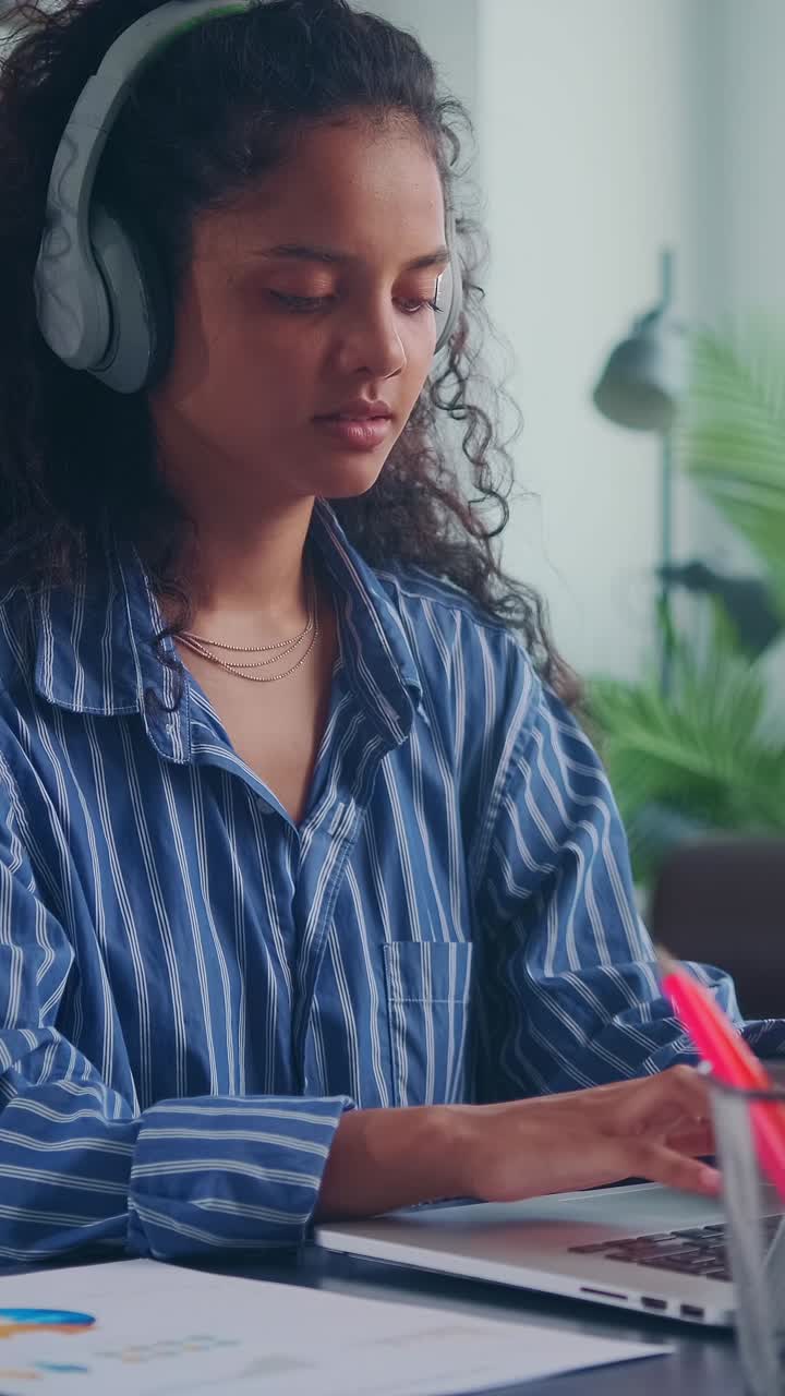 Young indian woman writer typing article on laptop sits at desk in office