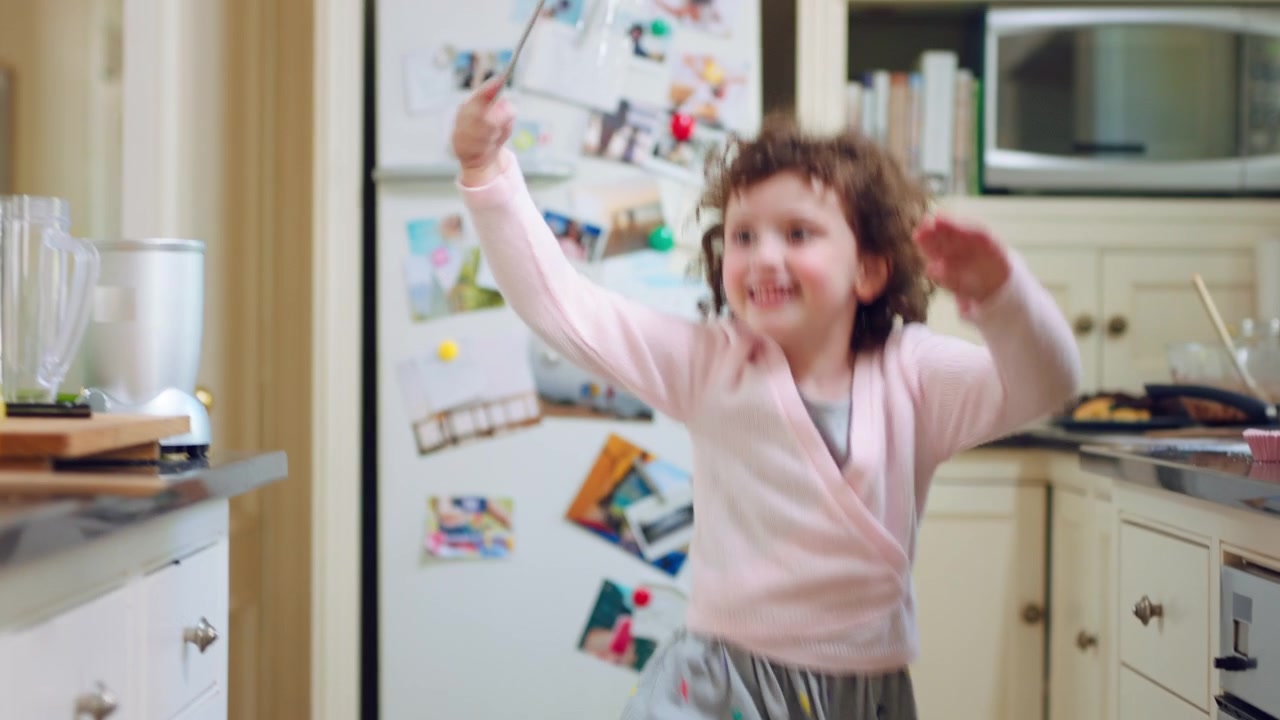 Little Girl Dancing and Playing with a Whisk in the Kitchen