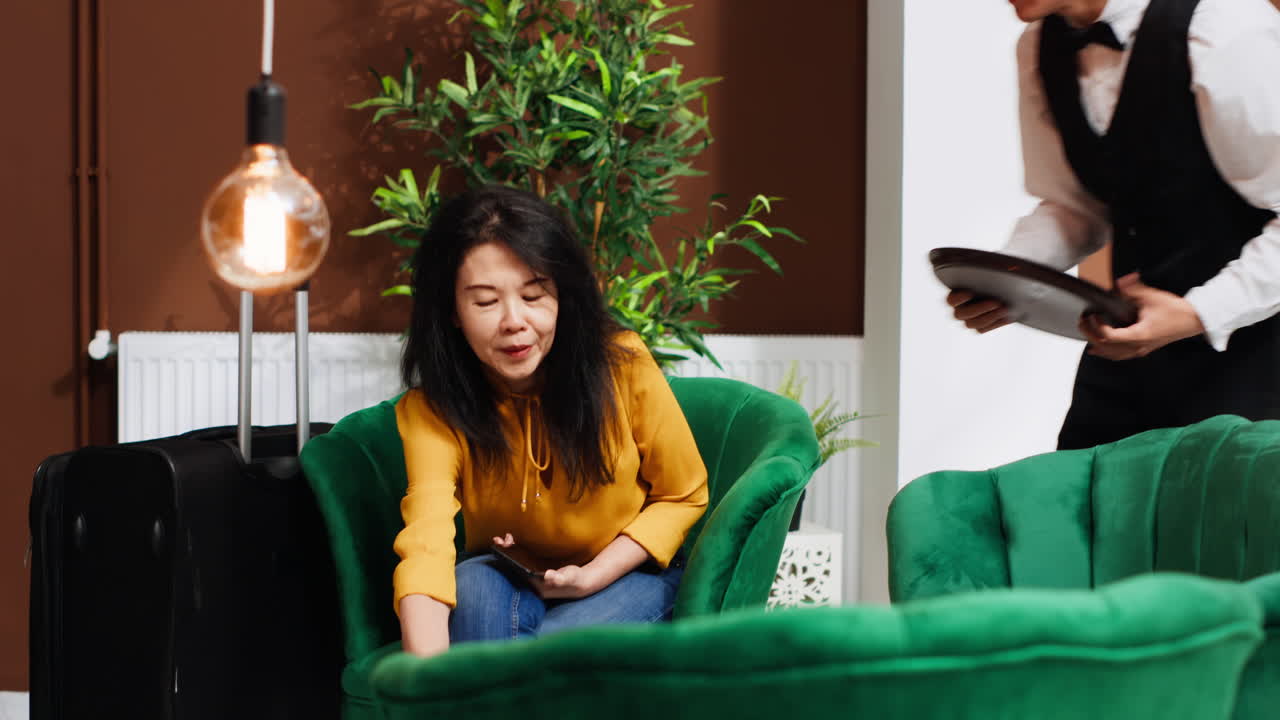 남자 웨이터 가 라운지 에 있는 여자 에게 커피 를 가져오고 있다