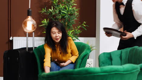 male waiter bringing coffee to woman in lounge area