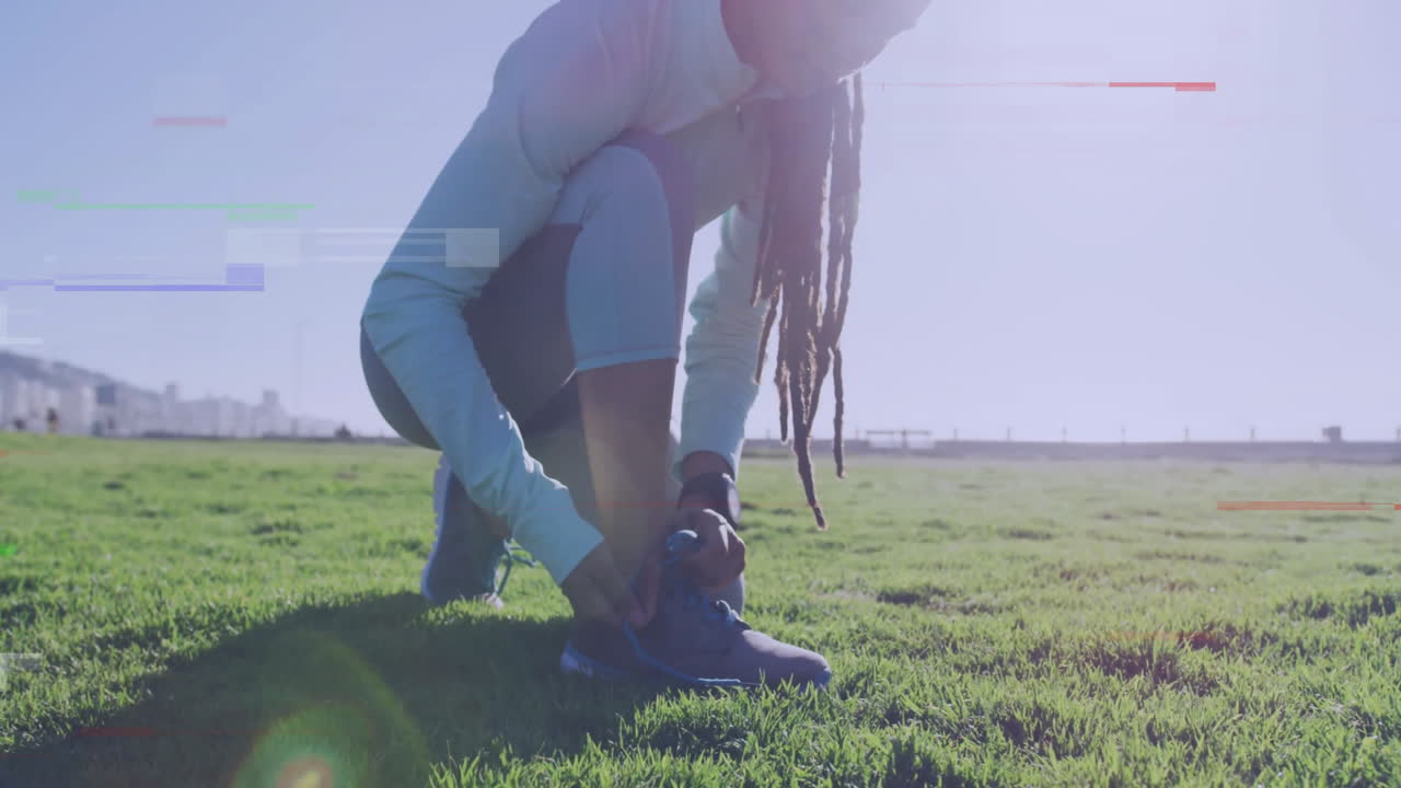 Tying shoelaces on grassy field, person enjoying bright sunlight outdoors
