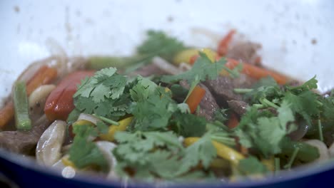 adorne la ternera a la pimienta negra con cilantro fresco picado y hojas de cilantro