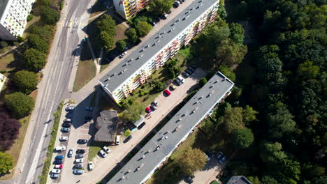 Toma-Aérea-De-Una-Calle-De-La-Ciudad-Con-Autos-Estacionados-Y-Edificios-Al-Lado