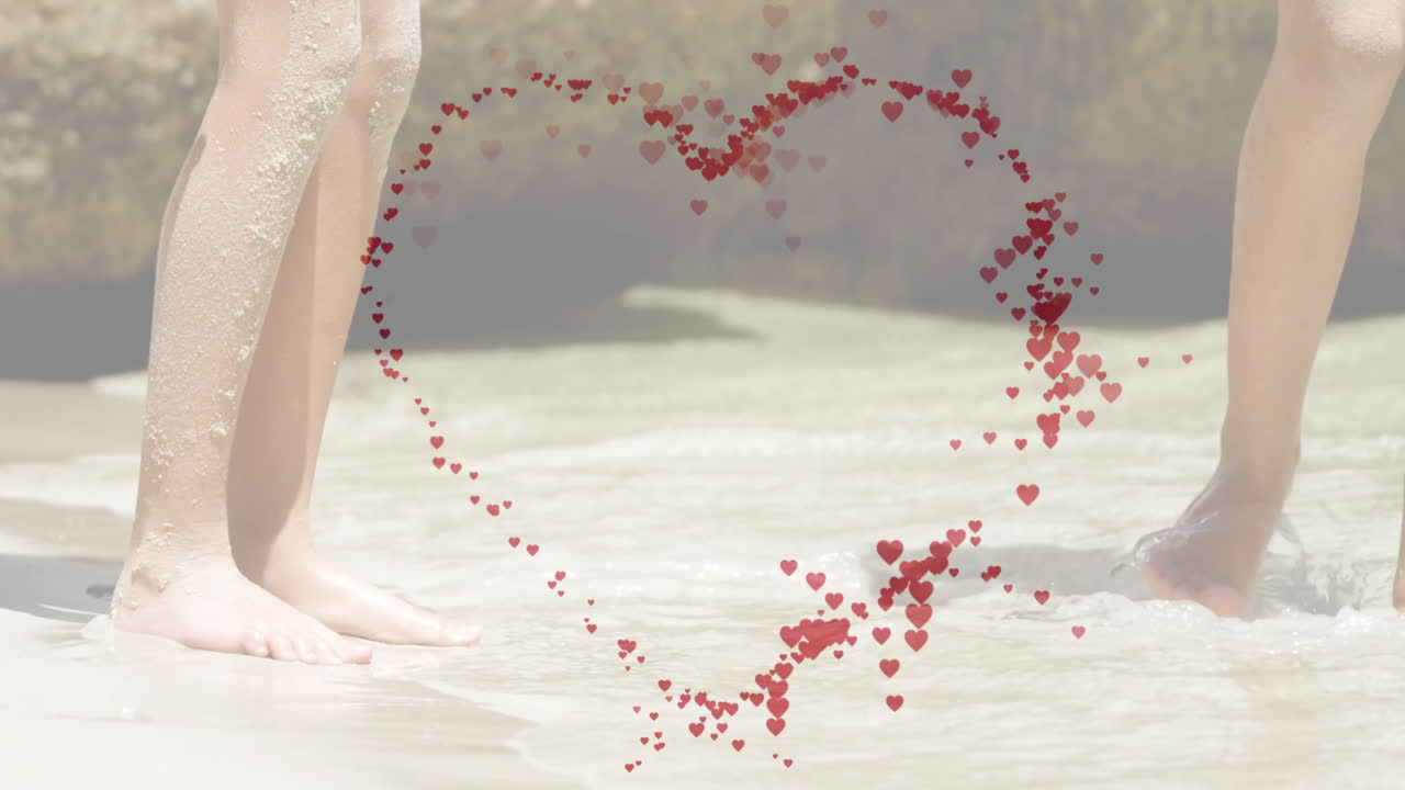 Heart-shaped animation of red hearts over people walking on sandy beach