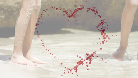 heart-shaped animation of red hearts over people walking on sandy beach
