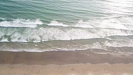 Vista-Lateral-Aérea-Sobre-La-Gente-Y-Las-Olas-Rompiendo-En-La-Playa-De-Arena