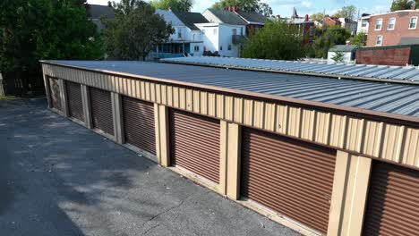 una fila de unidades de almacenamiento marrones con puertas de metal corrugado bajo un cielo despejado