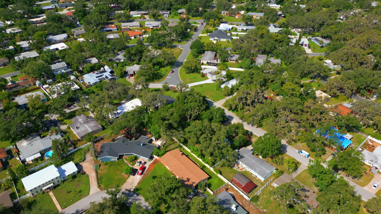 Drone high angle overview dolly of suburban area of Tampa with greenery, homes, and small road network below