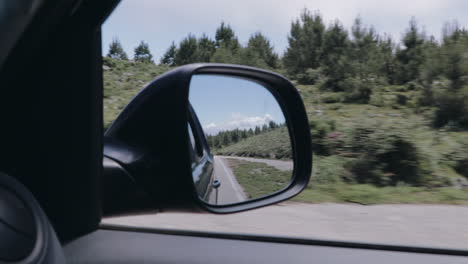 rear view through side mirror on mountain road in slow motion