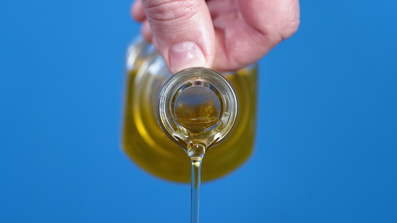 유리 비에서 올리브 오일을 는 사람의 손.