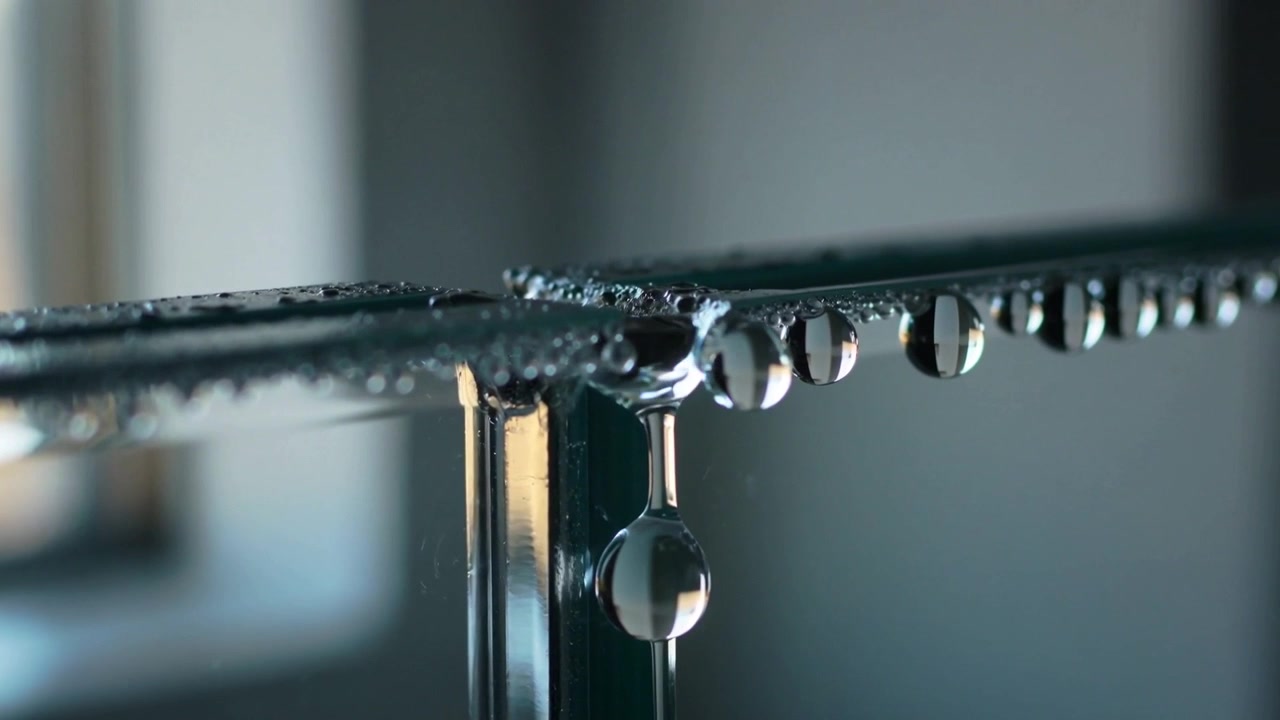 Growing pendant droplet at glass corner coalescing with adjacent beads and detaching under gravity