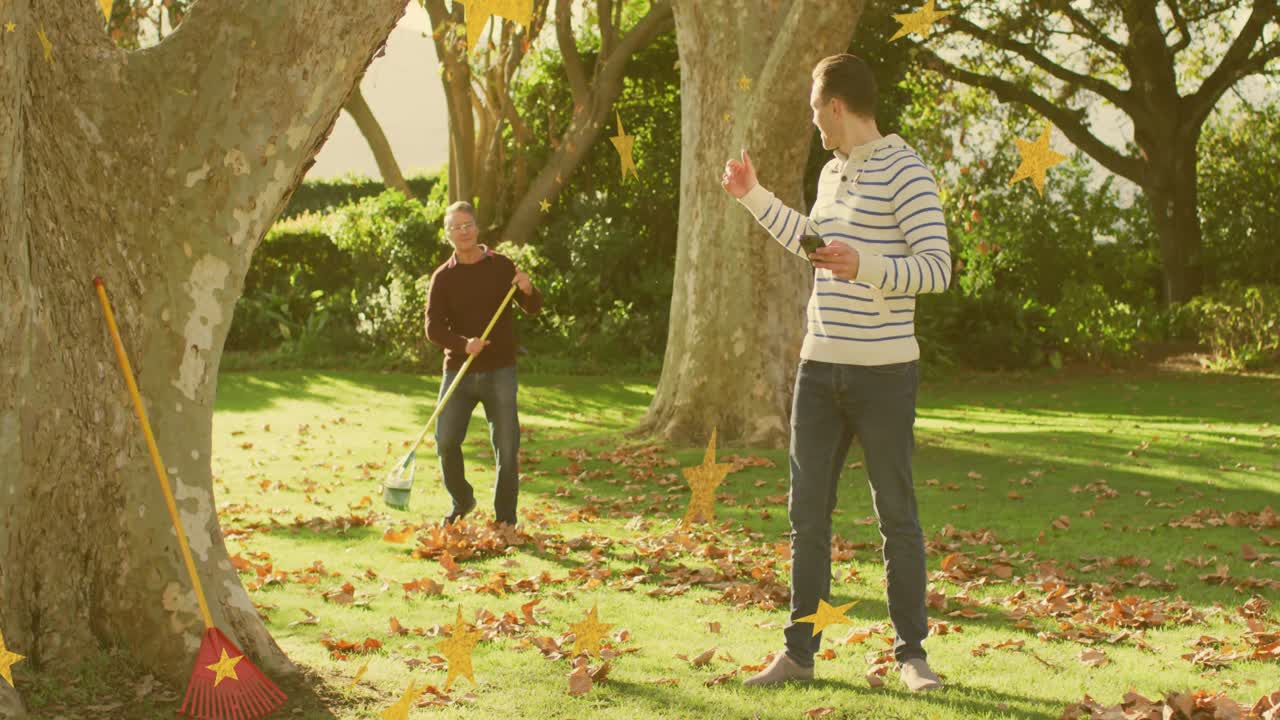 Mature man starting raking fallen leaves into piles, front man checking phone and gesturing in yard