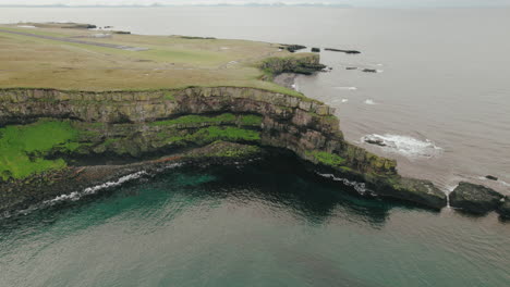 panorámica aérea que revela la pista de aterrizaje de un avión pequeño en una isla mugrienta, círculo polar ártico