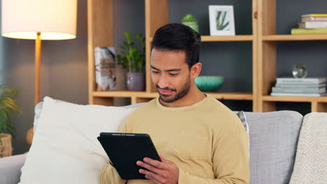 young man browsing on a digital tablet on a sofa