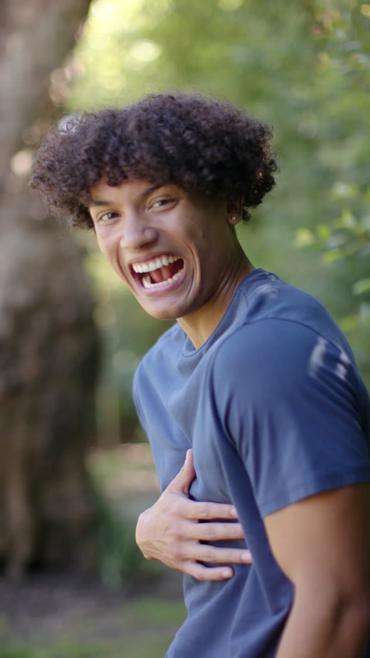 Vertical video: Young man laughing joyfully outdoors, enjoying sunny day in nature