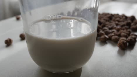 glass of horchata de chufa with tiger nuts scattered on white surface