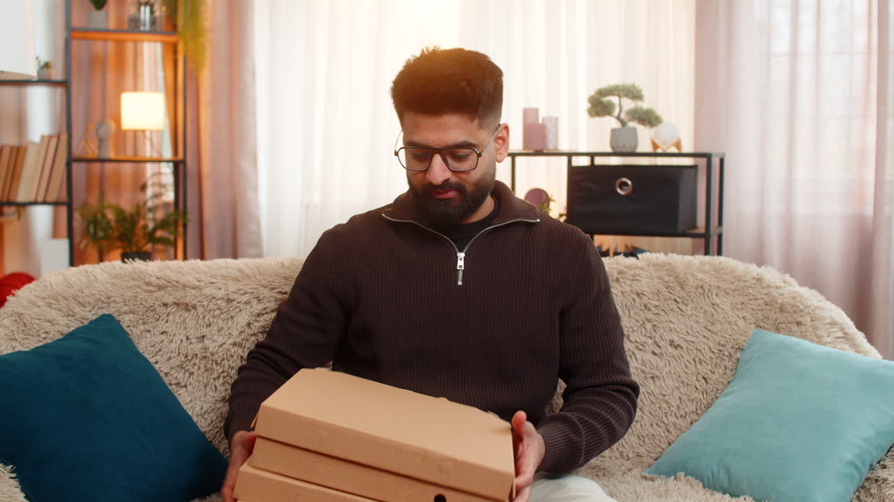 Indian man happily shops online using credit card and smartphone excited about new food delivery
