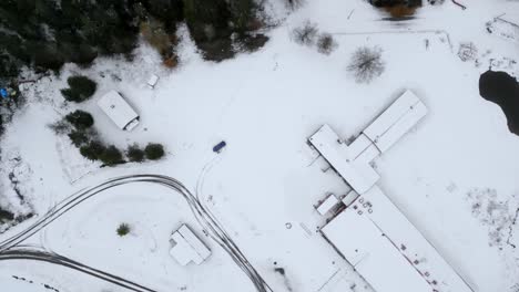 drone top shot subiendo y filmando algunos edificios y un estacionamiento vacío con nieve en, suecia