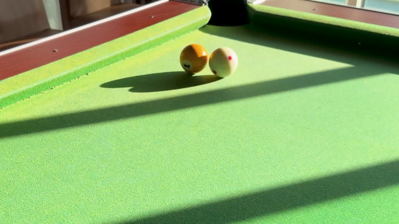 Una palla bianca colpisce una palla gialla in una buca d'angolo su un panno verde
