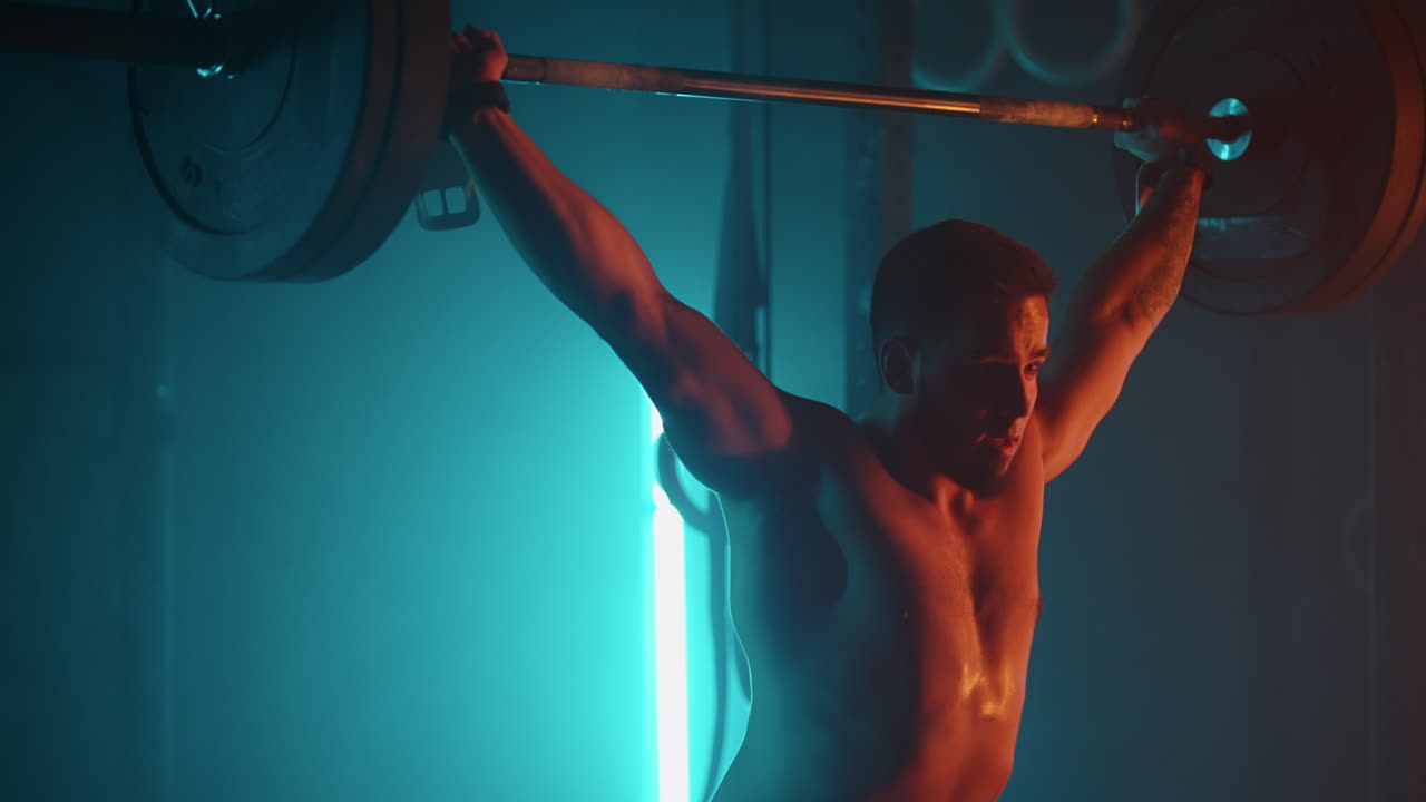 joven levantador de pesas está entrenando con barra en el gimnasio levantando pesas y bajando en el suelo