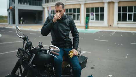 man drinking coffee on a motorcycle in the city