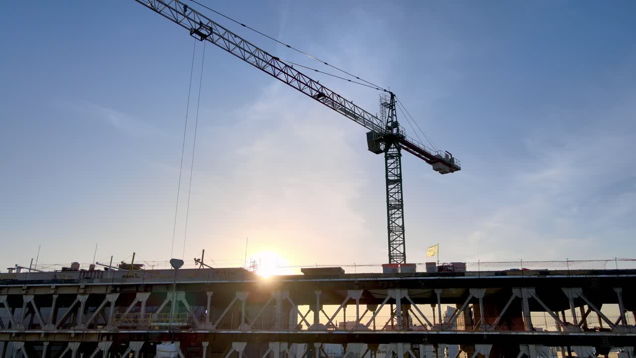 Construction site in city - construction crane being operated at sunset