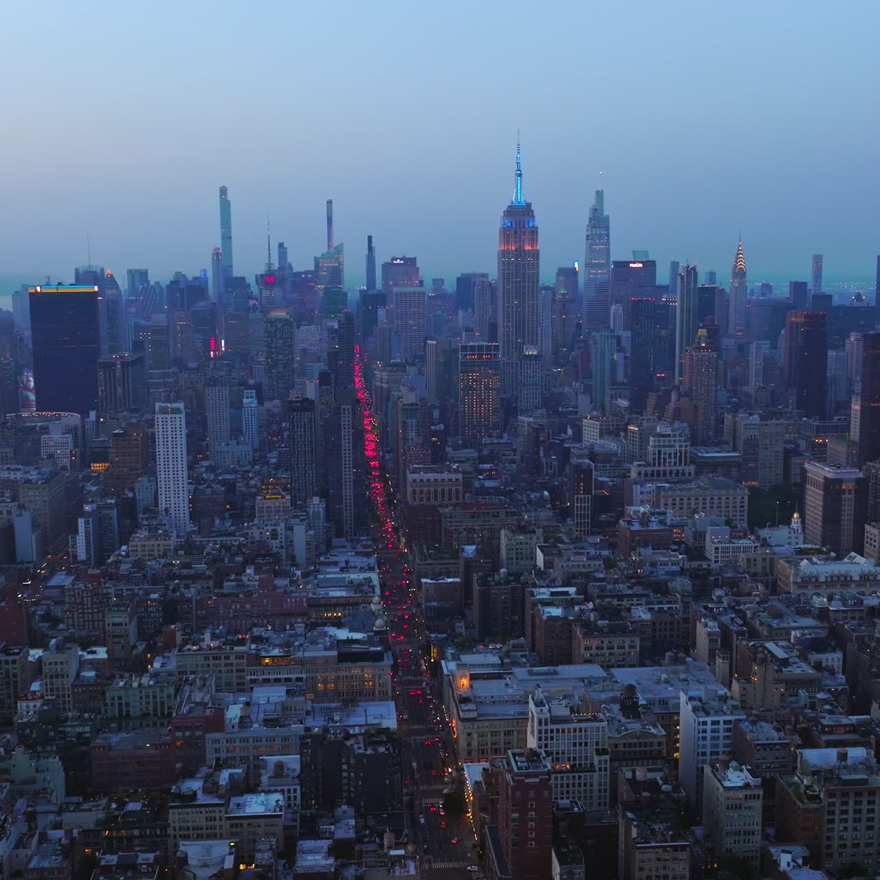 Impressive New York panorama after the sunset. Hundreds of cars with red lights on in the busy streets of metropolis. Aerial view