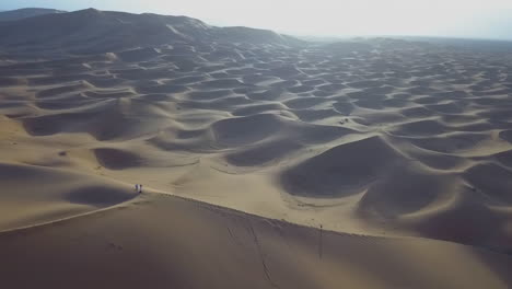 Amplia-Toma-Panorámica-De-Drones-De-Personas-Escalando-Dunas-De-Arena-Marruecos