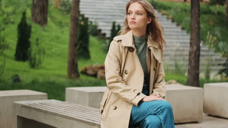 caucasian female student sitting in a bench outdoors.