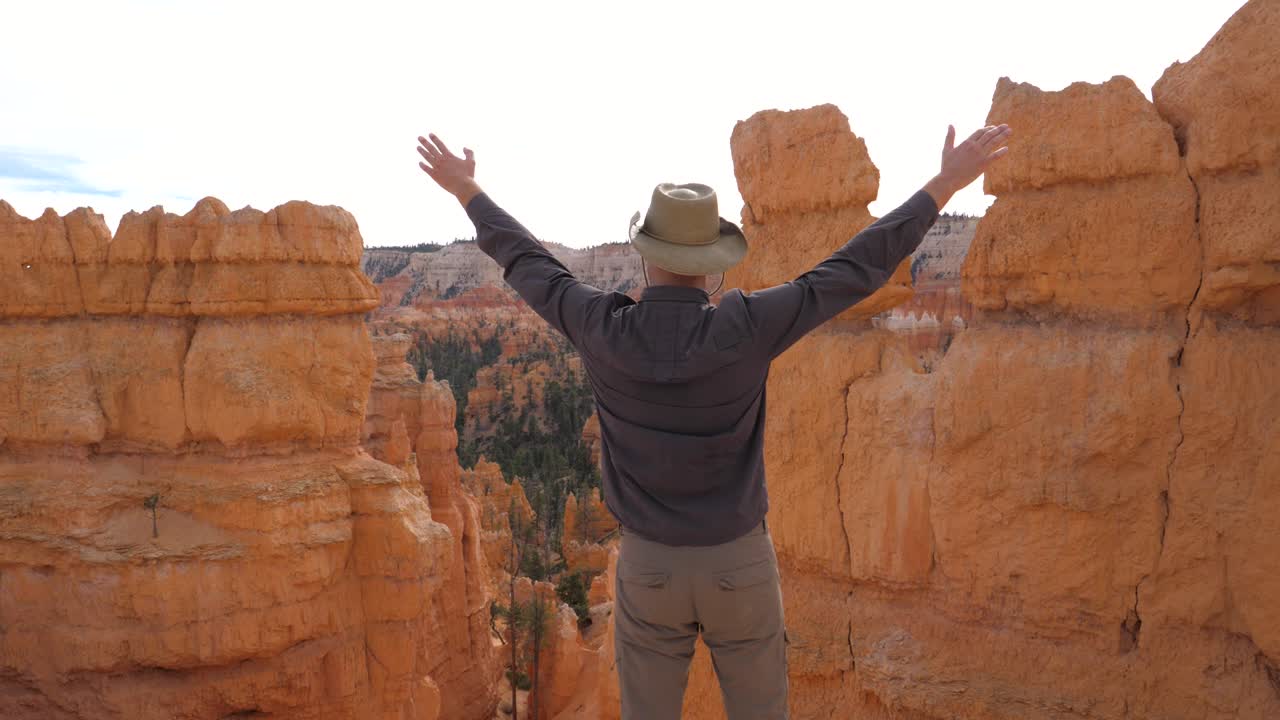 un hombre admira la naturaleza del cañón bryce, levanta la mano y se da la vuelta