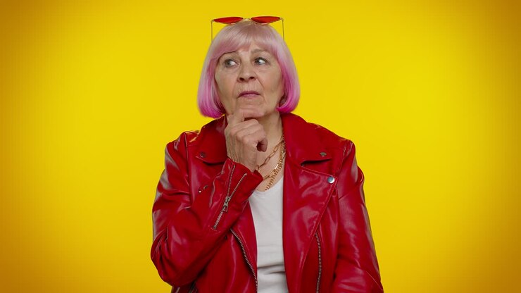Thoughtful clever senior old grandma woman rubbing her chin pondering a solution, doubting question