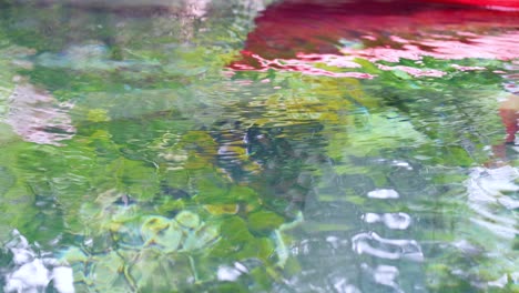 red kayak gliding over clear water in lush green canal