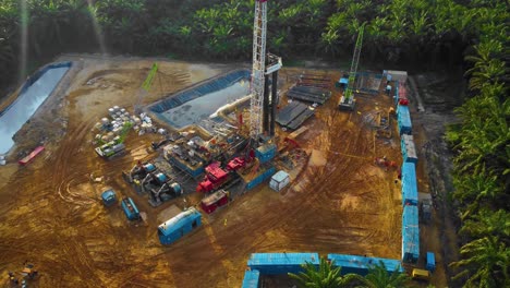 Cinematic-4K-Drone-Footage-of-Onshore-Drilling-Rig-equipment-structure-for-oil-exploration-and-exploitation-in-the-middle-of-jungle-surrounded-by-palm-oil-trees-during-sunset-and-high-oil-price