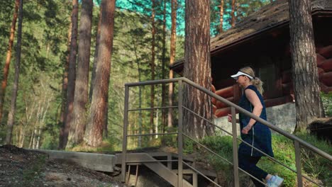 woman running upstairs in forest near a log cabin