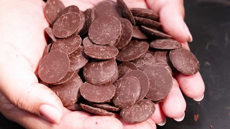 las manos acunan suavemente los discos de chocolate en las palmas de las manos.