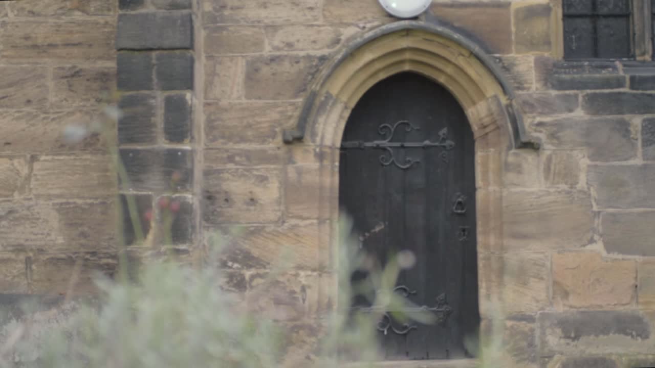 Gothic looking old black wooden door in stone church building archway