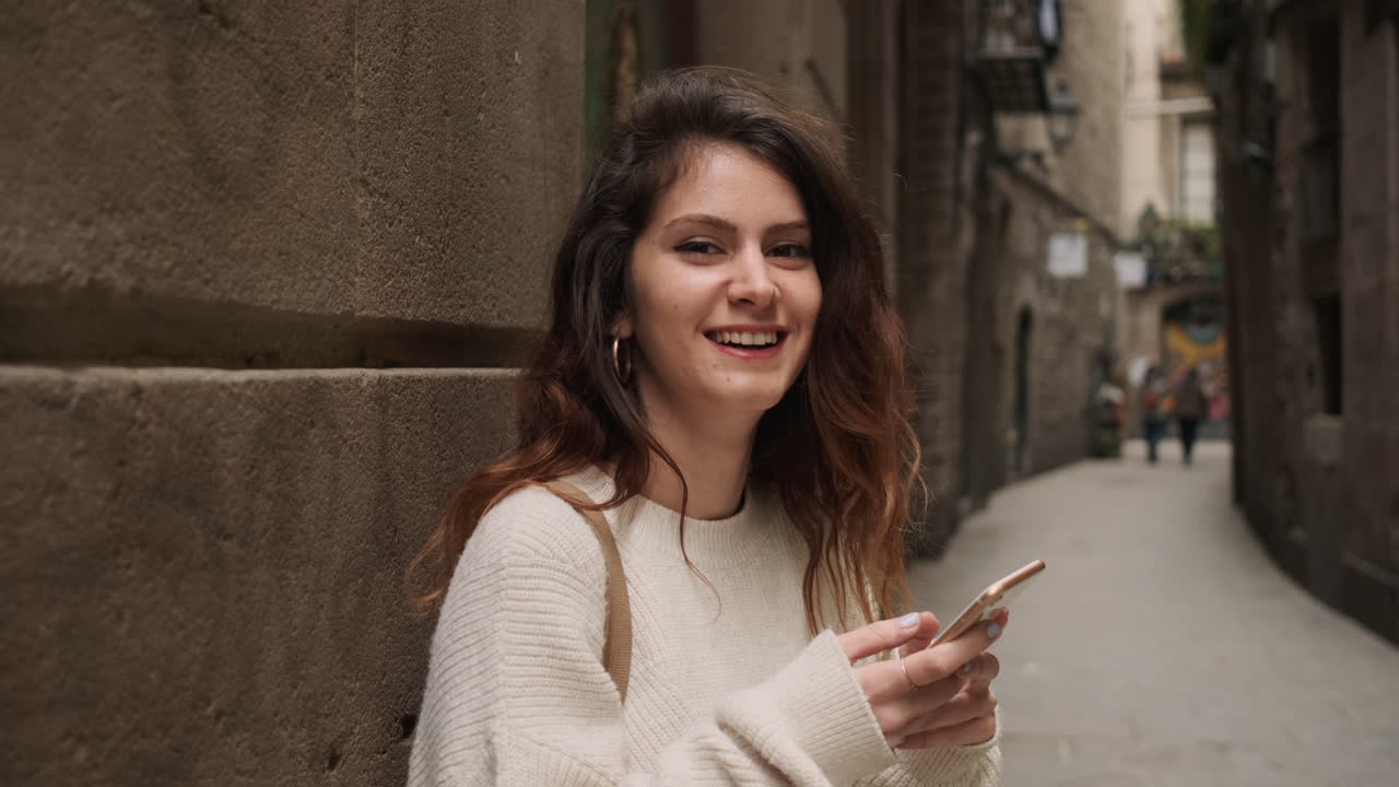 mujer mirando a la cámara mientras sostiene el teléfono celular