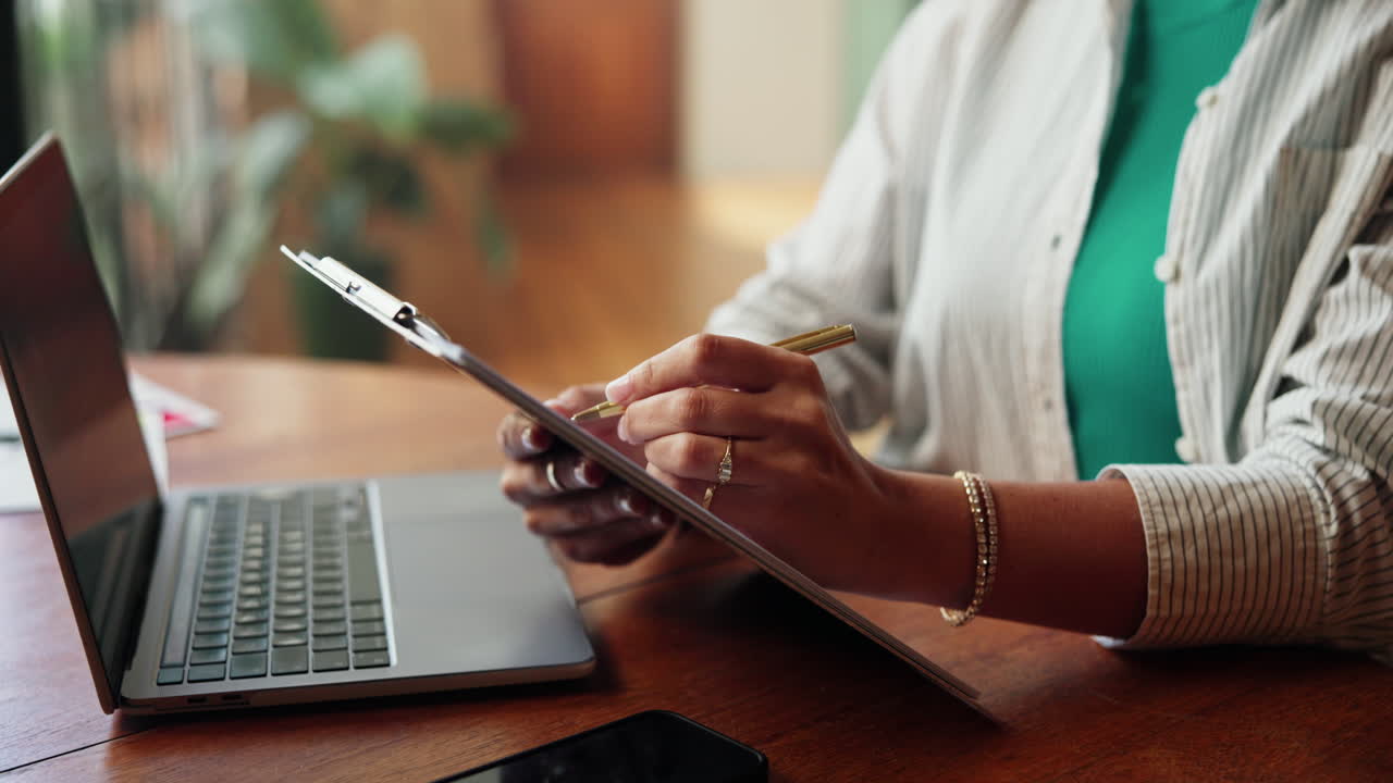 Close-Up of Person's Hands Writing on Clipboard at Desk