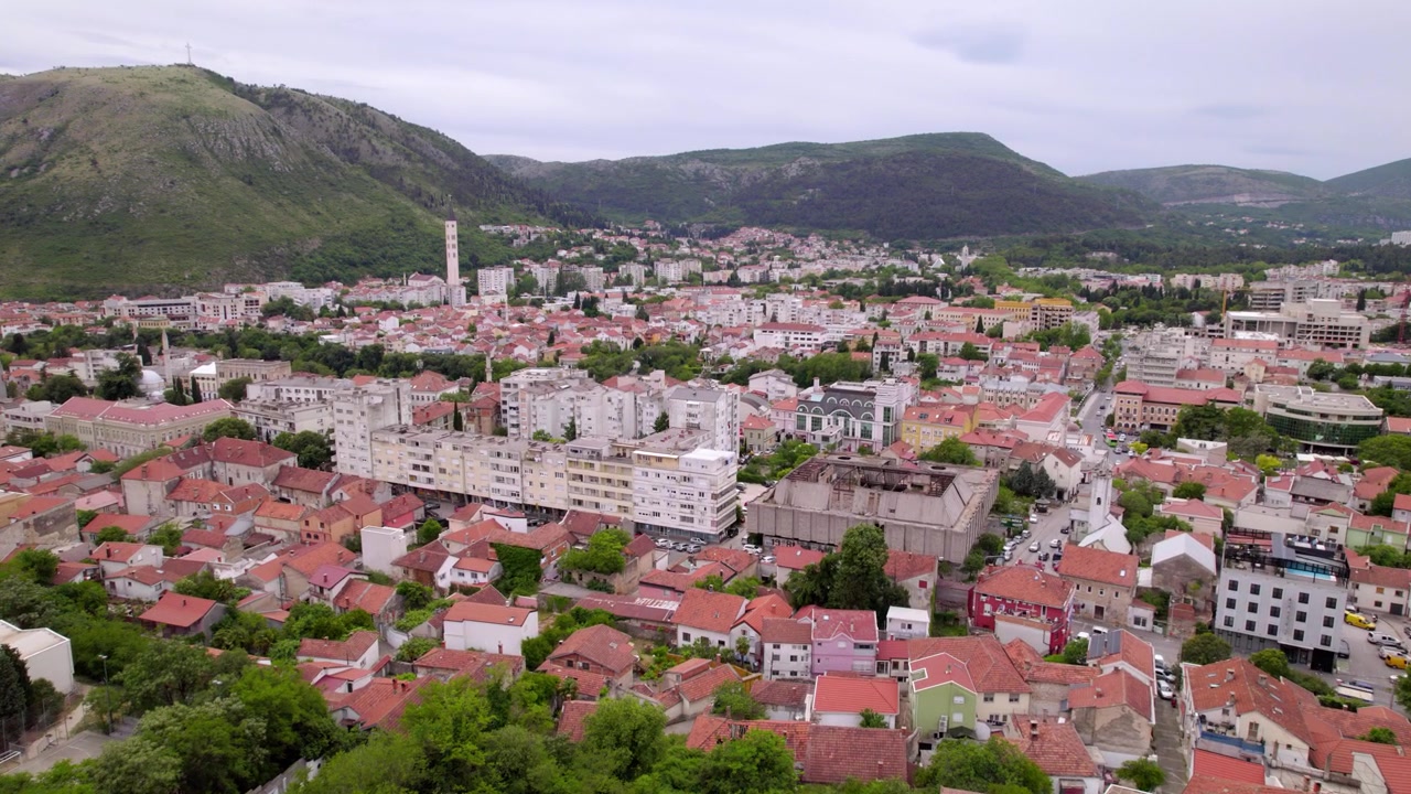 Letecké panorama centra města Mostar, obklopené kopci a hustou městskou zástavbou, záběr dronem, Bosna a Hercegovina.